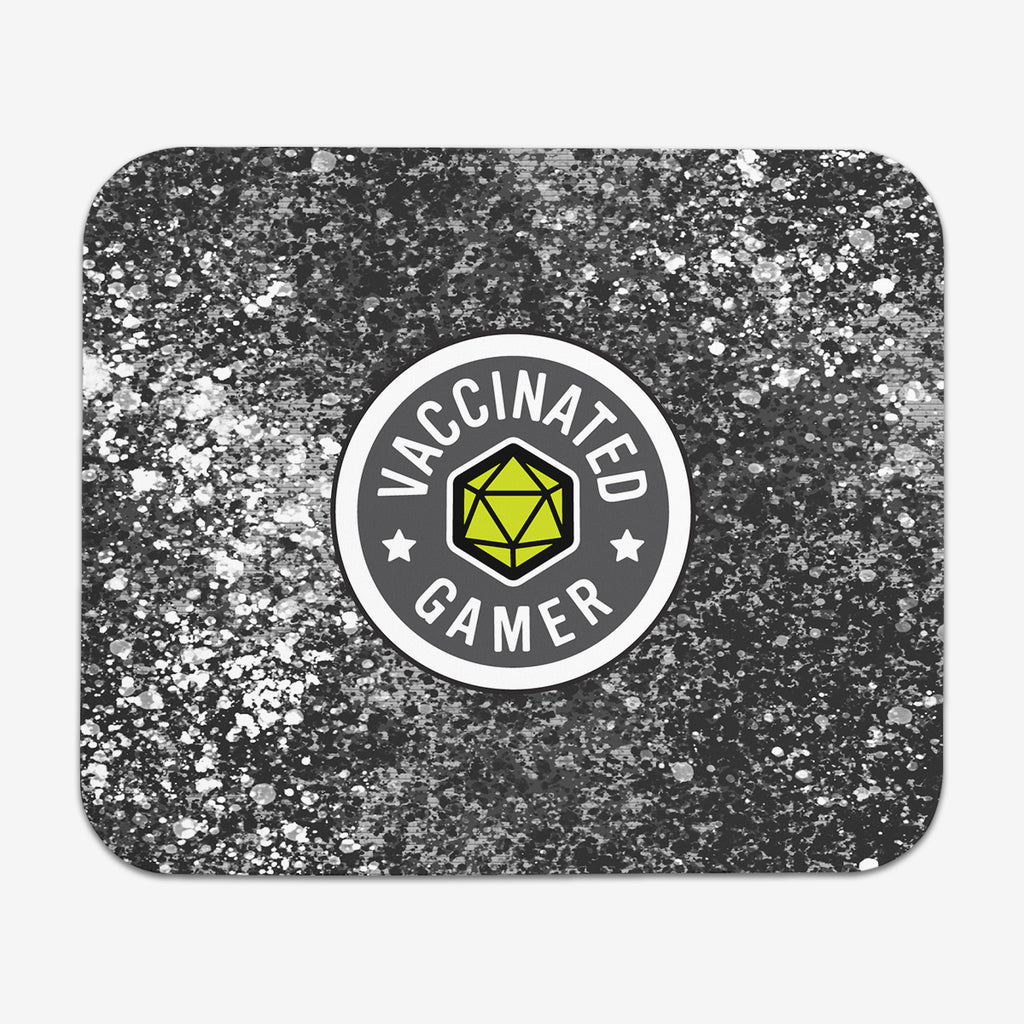 A classic mousepad with grey, white, and black splattered paint behind a circular logo. The logo is white and grey with a green 20 sided dice in the middle. The white text around the dice reads “Vaccinated Gamer.” “Vaccinated” is separated from “Gamer” by two white stars.