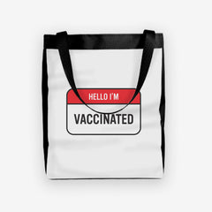 A white day tote with a red and white label at the center. The red part of the label reads “Hello I’m” in white text. The white part of the label reads “Vaccinated” in black text.
