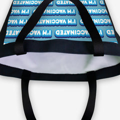 A close-up of a blue day tote with a blue and white bubble text pattern. The text that reads “I’m Vaccinated” is in white. Each of these has blue behind them, from the lightest shade to the darkest shade.