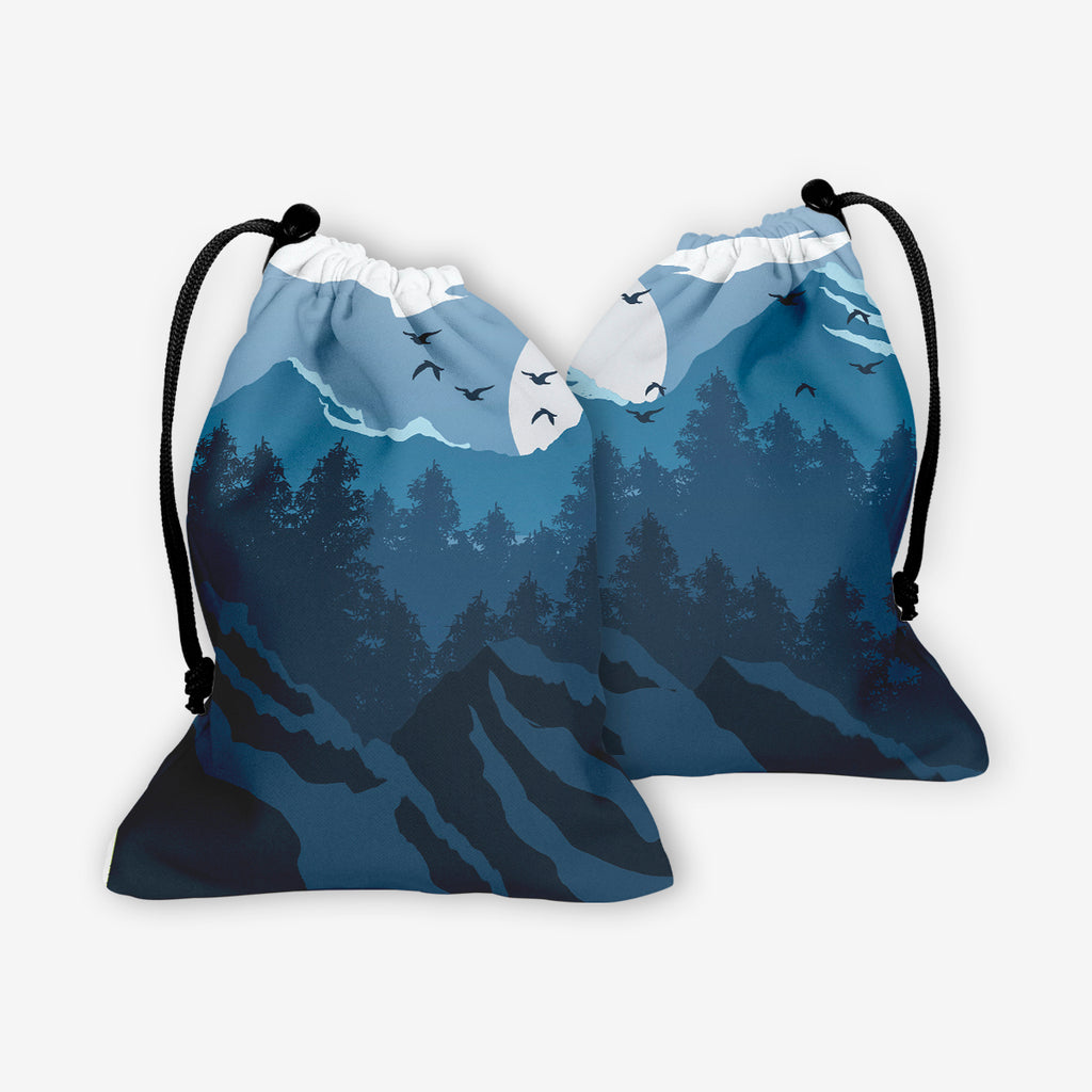 Blue Winter Forest dice bag by Carbon Beaver. A forest landscape. Everything is in shades of blue. The sun is setting behind the mountains and birds are flying in the sky.