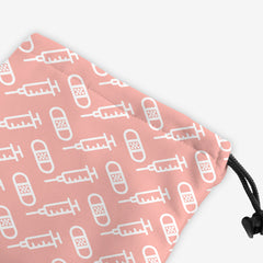 A close-up of a pink dice bag with a white pattern of bandages and vaccines.