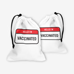 A front and back side of a white dice bag with a red and white label at the center. The red part of the label reads “Hello I’m” in white text. The white part of the label reads “Vaccinated” in black text.