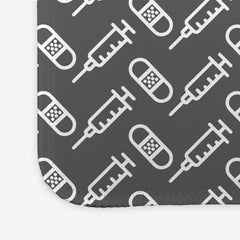 A close-up of the grey large gaming mousepad with a white pattern of bandages and vaccines