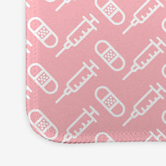 A close-up of the pink large gaming mousepad with a white pattern of bandages and vaccines