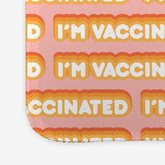 A close-up of a pink large gaming mousepad with an orange and white bubble text pattern. The text that reads “I’m Vaccinated” is in white. Each of these has orange behind them, from the lightest shade to the darkest shade.