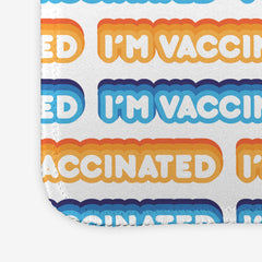 A close-up of a white large gaming mousepad with an orange, blue, and white bubble text pattern. The text that reads “I’m Vaccinated” is in white. Each of these has orange or blue behind them, from the lightest shade to the darkest shade.