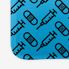 A close-up of the blue extra large gaming mousepad with a black pattern of bandages and vaccines