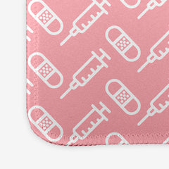 A close-up of the pink extra large gaming mousepad with a white pattern of bandages and vaccines