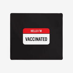A black extra large gaming mousepad with a red and white label at the center. The red part of the label says "Hello I'm" in white text. The white part of the label reads "Vaccinated" in black text.