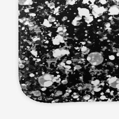 A close-up of a extra large gaming mousepad with grey, white, and black splattered paint.