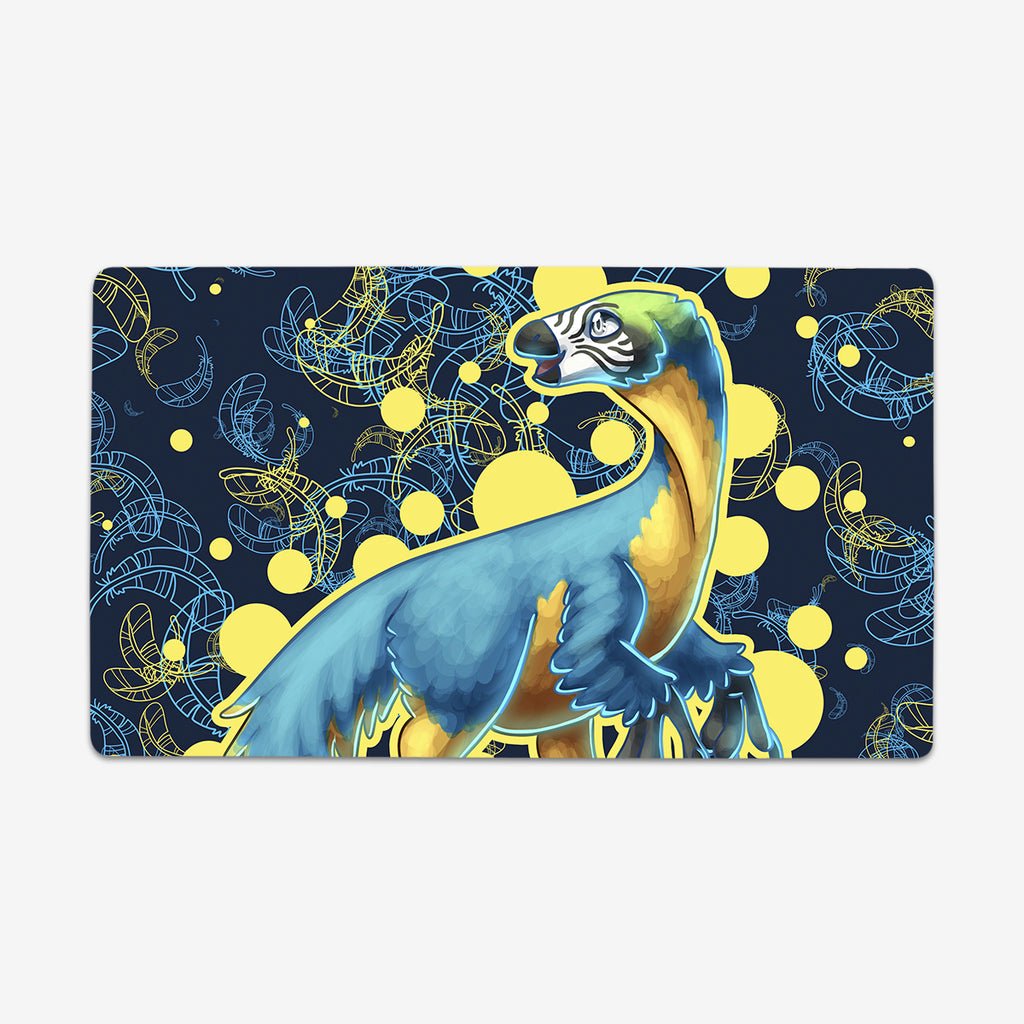 Therizinosaurus by Ian Haramaki. A Therizinosaurus stands in the middle of this playmat. The dinosaur has yellow and blue feathers, long claws, and a bushy tale. The background is dark blue with a light blue and yellow feather pattern.