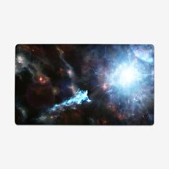Playmat of Going Beyond Light by Martin Kaye. On a black space background a star explodes emitting a bright white light. To the left of this explosion many other stars appear in different colors.