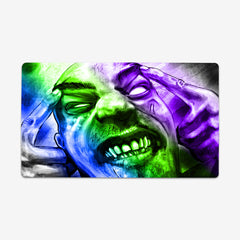 Playmat of Infected Mind by Why Try Designs. A blue, green, and purple drawing of a man with his hands on his head. He is making a face as if he's in pane. His eyes are all white, he has scars on his face, and all his teeth are showing.