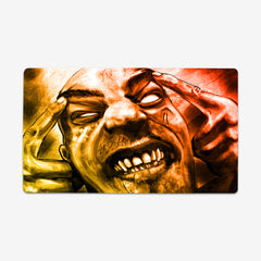 Playmat of Infected Mind by Why Try Designs. A Yellow and orange drawing of a man with his hands on his head. He is making a face as if he's in pane. His eyes are all white, he has scars on his face, and all his teeth are showing.