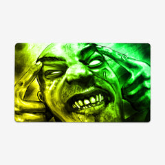 Playmat of Infected Mind by Why Try Designs. A yellow and green drawing of a man with his hands on his head. He is making a face as if he's in pane. His eyes are all white, he has scars on his face, and all his teeth are showing.